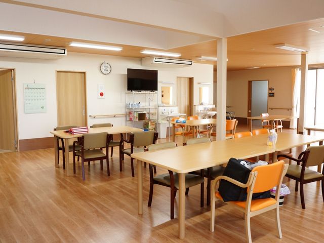 明るい食堂の空間 多目的室 広々としたダイニングエリアで、利用者様が集い楽しい食事のひとときを過ごせる設計です。木目調の温かみあるインテリアが印象的な場所となっております。