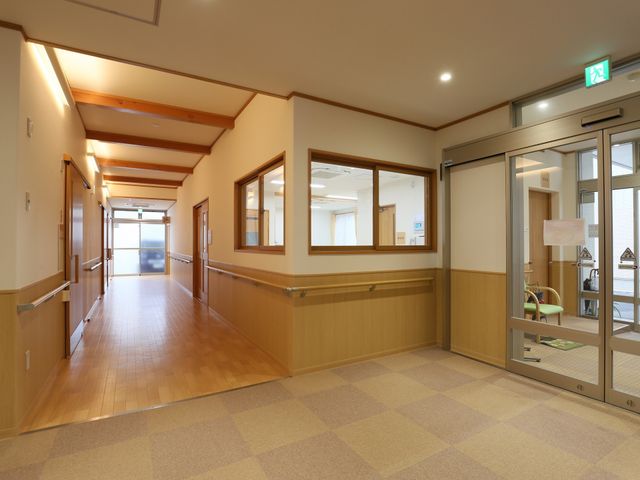 廊下の清潔な空間 ロビー 床材と天井のウッディな調和が心地よい廊下です。手すりも備えられ、安全に配慮された設計となっています。