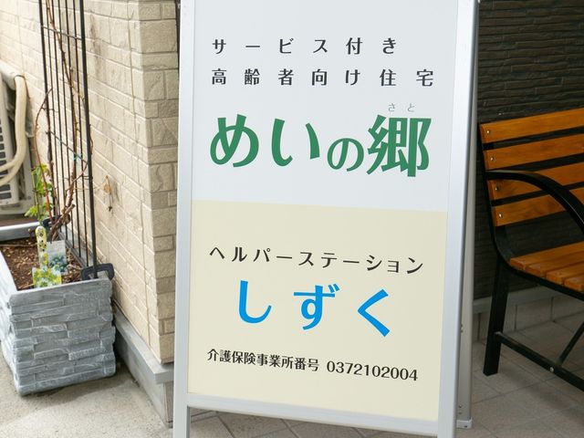 看板のある入口風景 看板 心温まるエントランスには、心地よい待遇が示された優しい色合いの看板がお出迎えします。就業をお考えの方には、温かい雰囲気が感じられる環境です。