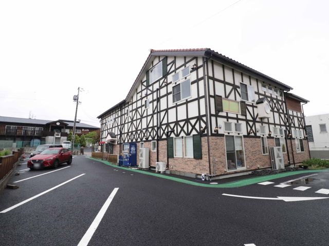 駐車場から見た施設外観 外観 木目とレンガの外壁が特徴の建物で、清潔感があります。広々とした駐車スペースが整備されており、アクセスも良好です。