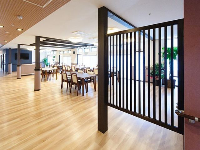 広々とした明るい食堂 多目的ホール 床の木目調が温かみを感じさせる食堂では、ゆったりとしたお食事の時間を過ごせます。天井からの自然光が空間を明るく照らしています。