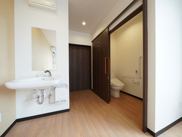 居室内の洗面台とトイレ 洗面台 清潔感のある洗面スペースとバリアフリーのトイレ設備が揃っています。使い勝手と安全を考慮した設計で、ゆったりとした日々を過ごすことができます。