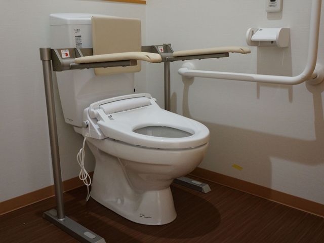 バリアフリートイレ設備 トイレ 手すり付きで安全性が高いトイレです。介護を通じて、安心してご利用いただける環境を整えています。