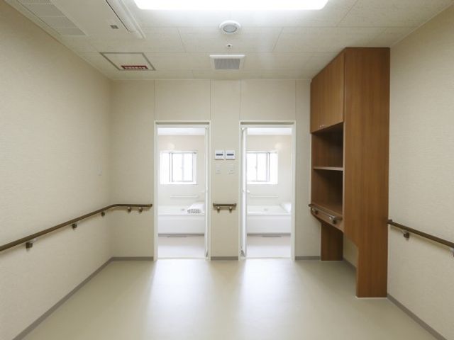 清潔感ある廊下 浴室 広々とした廊下は、手すりが完備されており、安全に配慮された設計です。壁の色や照明も含め、心地よい環境で働ける空間がここにあります。
