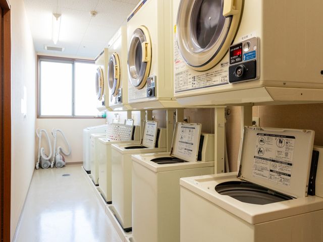 洗濯機が並ぶ部屋 コインランドリー 手軽に使用できる洗濯機が並び、清潔で明るいスペースです。到着後すぐに作業を始められます。