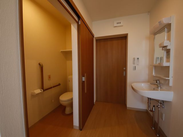 居室内のトイレと洗面台 トイレ･洗面台 広々とした使い勝手の良い居室内トイレです。安全性を考えた手すりや、洗面設備も整えられ、清潔な環境が保たれています。