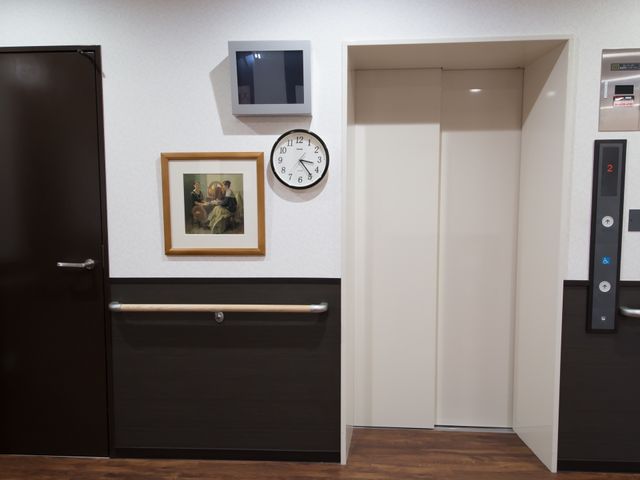 モダンなエレベーター前 エレベーター付近 清潔感のある壁と床が特徴のエレベーター前です。手すりが整っており、安心してお過ごしいただける設計になっています。