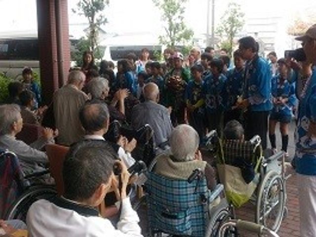 車椅子の利用者と訪問者の集い イベント 活気に満ちたエントランスは、ご利用者が訪問者とのふれあいを楽しんでいる生き生きとした場所です。優しい会話や笑顔が交わされ、暖かな雰囲気を感じることができます。