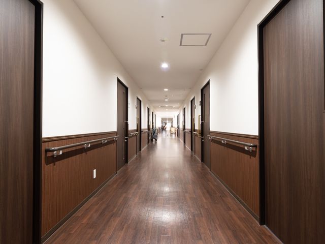 明るく広い施設の廊下 通路 ゆとりのある廊下は落ち着いた色合いで設計され、静かな時間を過ごすには適した環境です。安全に気を配りながら、快適な職場を求める方におすすめします。