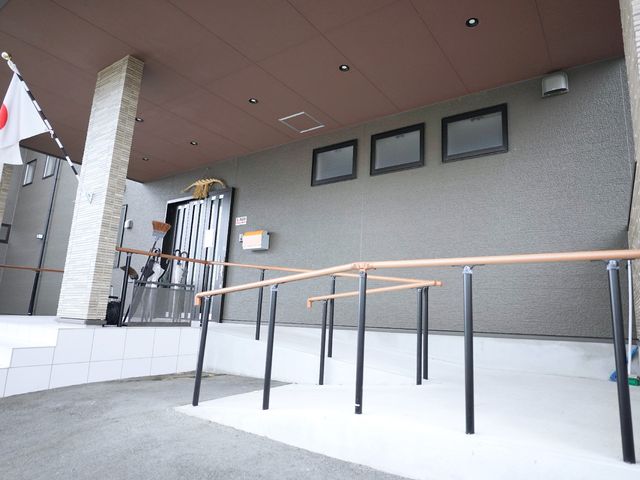 施設の入り口と手すり 玄関 手すりが設けられた広々としたエントランスです。利用者の安全と利便性を考えた設計が行き届いています。