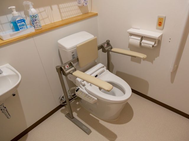 バリアフリー対応のトイレ トイレ 支援バー付きのトイレで、どなたでも使いやすい設計になっています。安全と快適さを考慮した設備です。