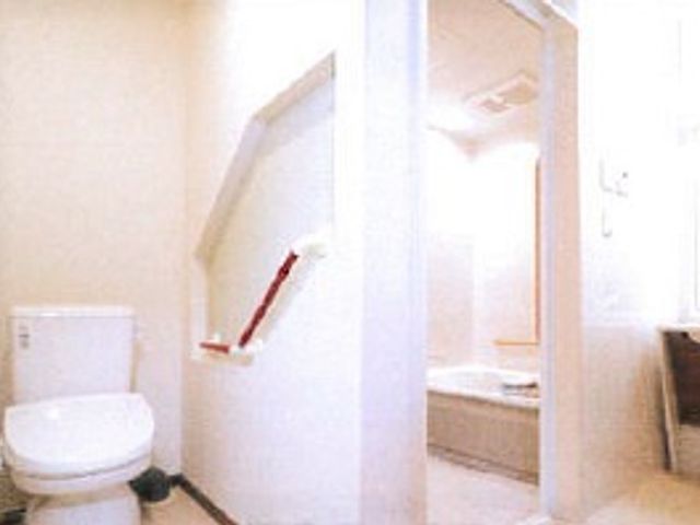 バリアフリー設計の浴室 トイレ 手すり付きの清潔なトイレと広々とした浴室が見えます。利用者の安全と快適さを考えた造りです。