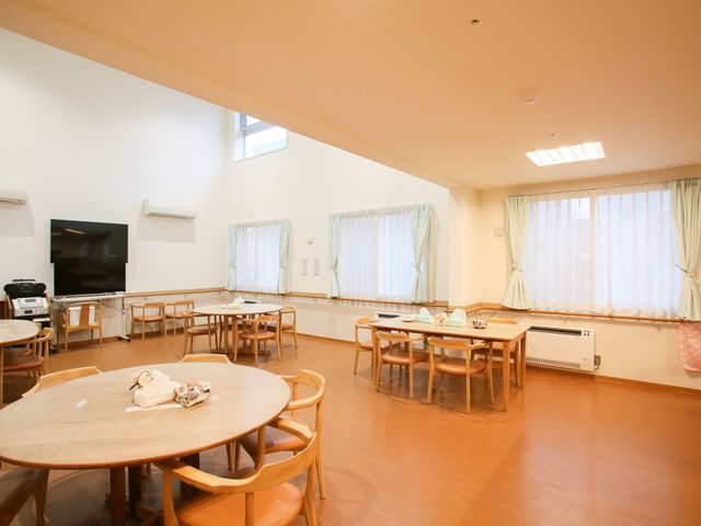 広々とした空間の食堂 ダイニング 窓から自然光が差し込む、温かみのある食堂です。円卓が並び、誰もが気軽に会話を楽しめるように配慮されています。