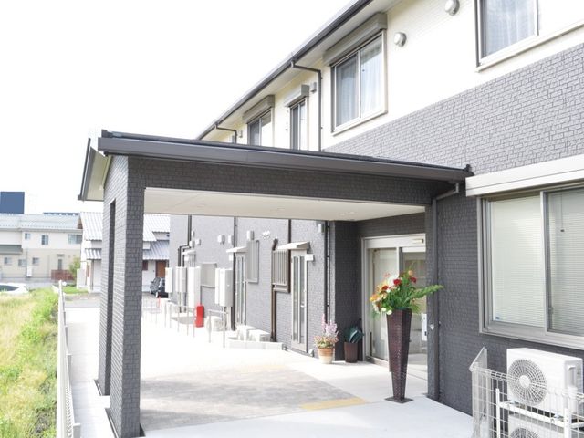 明るいエントランス前 玄関 ゆったりとした通路があり、心地よい出迎えを提供しているエントランスが特徴です。清潔感のある外観は、働く環境への期待を高めます。