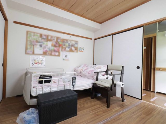 居心地の良い洋室風空間 居室 居室には柔らかな光が差し込み、壁には個性的な装飾が施され、安らぎと過ごしやすい環境が整っています。折り畳み椅子と安全ベッドも配置されており、快適な個人空間を提供しています。