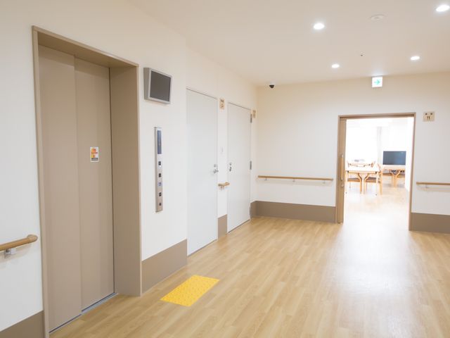 明るい廊下とエレベーター エレベーター 設備の整った廊下が確認でき、先にはゆったりとしたダイニングスペースが見えます。明るく開放的な空間でのお仕事をご検討ください。