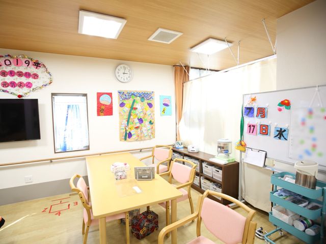 多機能な明るい部屋 食堂 明るい照明と色とりどりの手作り装飾が訪れる人を出迎える心地よい空間です。日常の様々な活動が行われる場所として、皆様をサポートいたします。