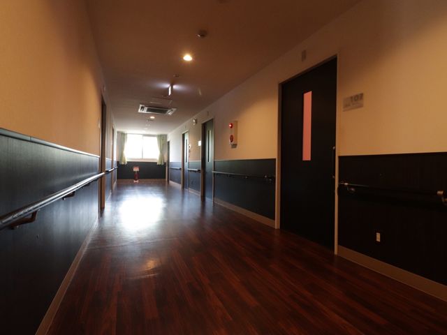広々とした廊下 通路 手すりが設置された落ち着いた色合いの廊下です。静かで安全な環境を提供しています。
