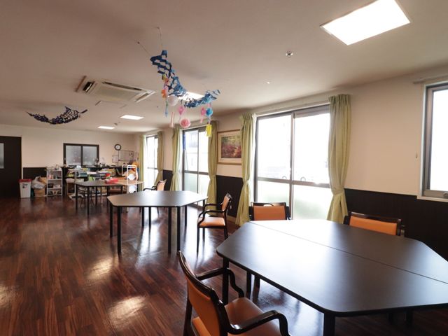 広々とした共用スペース 共有スペース ゆったりとした多目的室は、天井からの装飾も楽しんでいただけ、日中は自然光が差し込む明るい場所です。デイサービスなど、様々な活動に対応しています。
