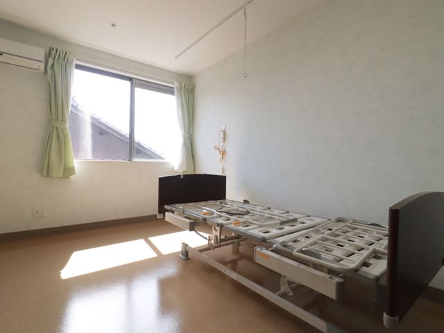 日差しが入る明るい居室 居室 陽光が差し込む広々とした部屋です。医療用のベッドも設置され、快適な環境が整っています。