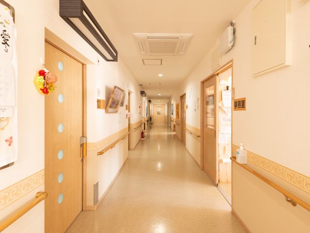 廊下の明るい景観 廊下 手すりが備わり、明るく清潔な通路が広がっています。壁には装飾や掲示物があり、日々の生活に彩りを加えています。