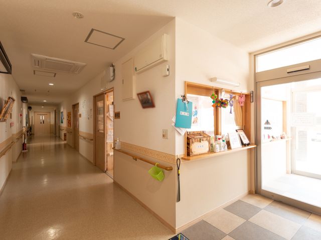 暖かい光の廊下 廊下 清潔で広々とした廊下は、日差しの中で明るく、安らげる空間を提供しています。廊下沿いには情報掲示板や装飾があり、訪れる人に温かい印象を与えます。