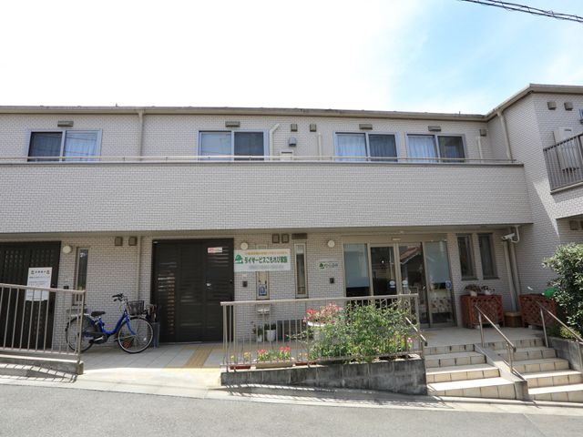 施設正面玄関と花壇 外観 手すり付きの階段と、訪れる方を温かく迎える花々のある明るいエントランスです。安全性と心地よさに配慮した設計となっています。