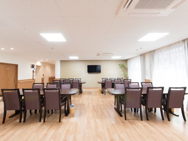 快適なダイニング空間 共有スペース 床の木目調と調和する落ち着いた色の家具が配置され、心地よい光が差し込む明るい食堂です。集いや食事の時間を居心地良く過ごせる環境が整っています。