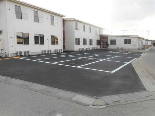 白い壁の建物と駐車場