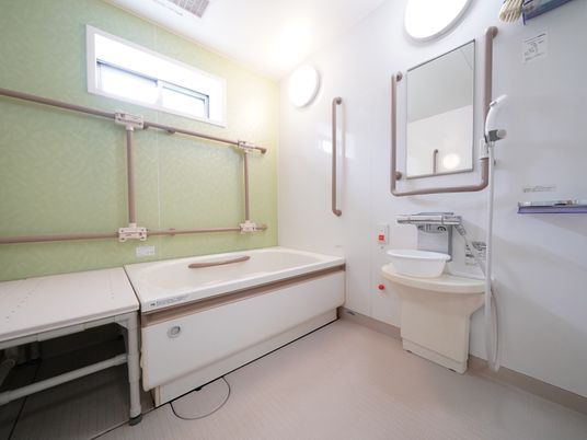 白を基調とした清潔な浴室は小窓から光が差し込みとても明るい。壁に２つの照明と鏡と非常ボタンが設置されている。