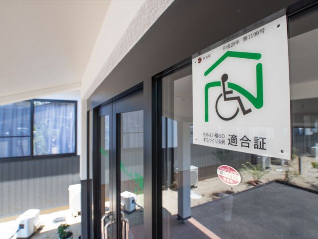 バリアフリー表示のエントランス 玄関 車椅子マークが目印の明るいエントランスは、来訪者を温かくお迎えします。ゆったりとした通路で安全な移動ができる設計になっています。