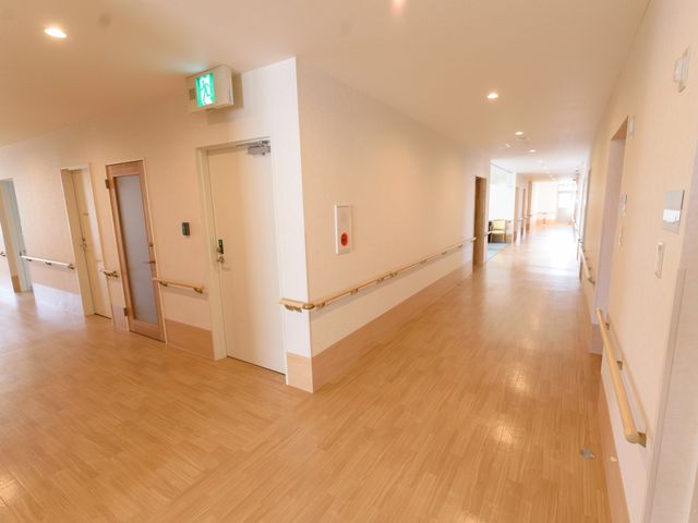 明るい施設の廊下 通路 ゆったりとした幅の廊下は、手すりが整っており、安全にご移動いただける設計です。明るく清潔感がある空間で心地よい日々をお過ごしいただけます。