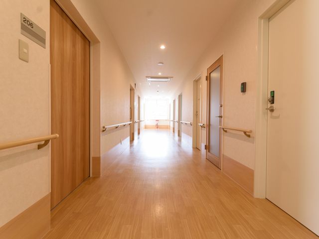 廊下の明るく清潔な光景 通路 手すりが設置された廊下は、ゆったりとした空間で、移動が楽な環境です。清潔感があり、明るい雰囲気が心地よい職場をご提供します。