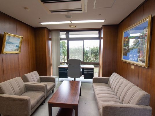 施設の写真 ローテーブルやソファが置かれている談話室。窓際にはデスクが設置されており、壁には絵画が飾られている。