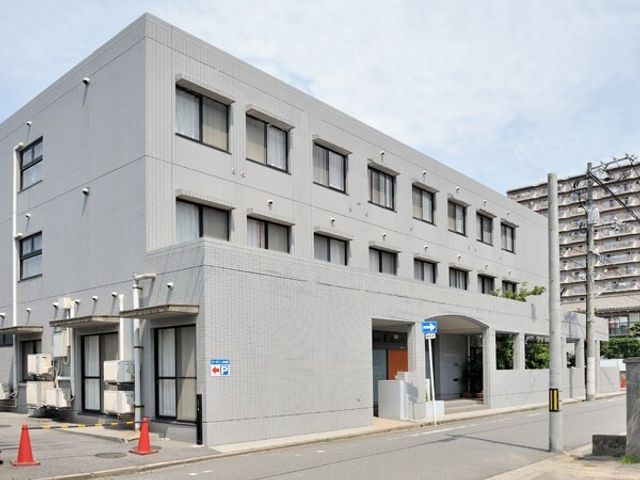 灰色の建物のエントランス 外観 広々としたエントランスが備わったモダンな建物です。安心できる勤務環境をお探しの方に適しています。