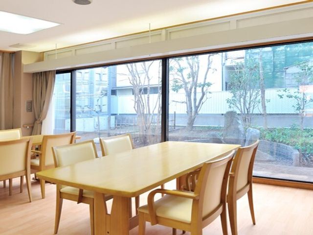 光が満ちる明るい食堂 リビングダイニング 床から天井までの窓から自然光が差し込む、明るく落ち着いた雰囲気の食堂です。広々としていて、ご利用者が心地よい時間を過ごせる空間となっています。