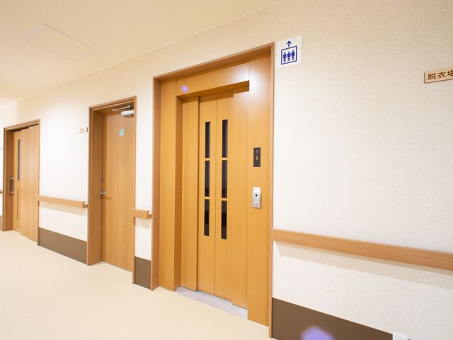 廊下の清潔な居室入口 エレベーター 安全とプライバシーを守る、シンプルで落ち着いたデザインの居室入口です。すっきりとした廊下が心地良い勤務環境を演出しています。