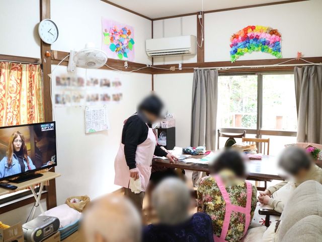 和室でくつろぐ人々 共有スペース アットホームな雰囲気の共有リビングです。スタッフの方が穏やかな対応をされており、利用者の方々も和やかに過ごされています。