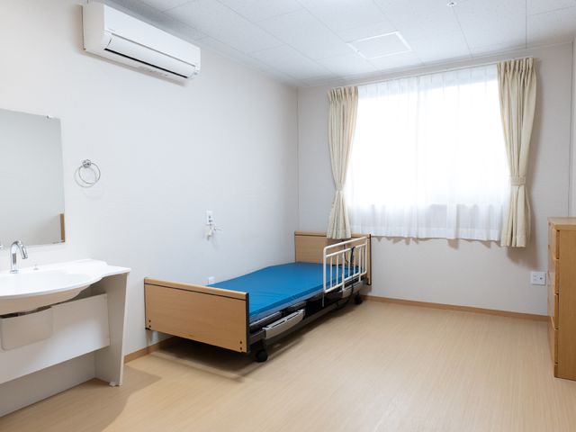 清潔な居室の一角 居室 床からベッド、洗面台まで清掃が行き届き、居心地の良い空間を大切にしています。ゆとりある間取りで日々の暮らしやすさを追求しています。