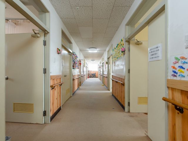 廊下とドアが並ぶ施設内 廊下 壁に飾られた工作品が暖かみのある雰囲気を醸し出している廊下です。清潔感のある空間で、日々の業務に取り組むことができます。