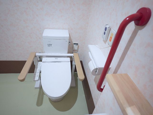 手すり付きのトイレ設備 トイレ 安全に配慮されたトイレは、手すりが設置され快適な利用が可能です。また、座面の高さ調整機能がついており、自立支援を促しています。