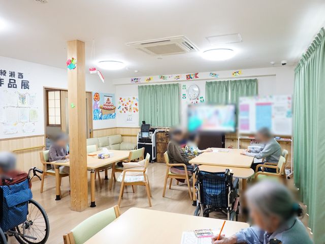 活気あるリビング風景 共有スペース 木のぬくもり感じる共有スペースで、利用者の皆様とのコミュニケーションを大切にしています。