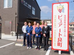 スタッフ一同が笑顔で立つ外観