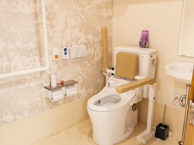 バリアフリー設計のトイレ トイレ 手すりが設置された落ち着いた色合いのトイレ。安心してお使いいただける配慮がされています。