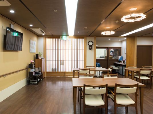 和風のドアが落ち着きをかもし出している食堂である。事務室が隣にあり、テレビや手すりが完備されている。