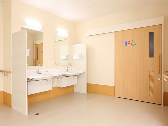 明るい洗面室とトイレの扉 トイレ（食堂） 清潔感のある洗面スペースが整っています。手すりも設置され、使いやすさに配慮されたデザインです。