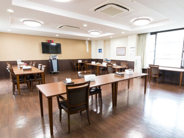 広々とした食堂の空間 共有スペース ゆったりとした食堂では、利用者さまが集いお食事や交流を楽しめるように設計されています。窓から自然光が差し込む明るい雰囲気の中、心地よい時間を過ごせます。