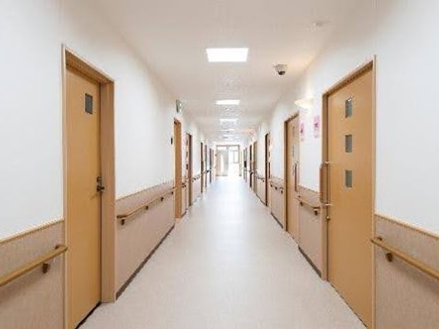 明るい廊下 廊下   手すりが両側に設置された、まっすぐ続く明るい廊下です。部屋の出入りがしやすい配置で、移動のしやすさが感じられます。