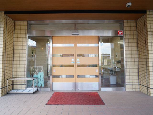 エントランスの自動ドア 玄関 広々としたエントランスは自動ドアで、出入りがしやすく設計されています。働く人にとって、訪れる方々を心地よくお迎えできる環境です。
