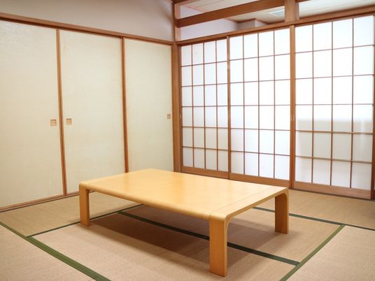 ふすまや障子で仕切られた和室がある。８畳の部屋の中央部に、縁が丸みを帯びた天板の背の低いテーブルが置かれている。